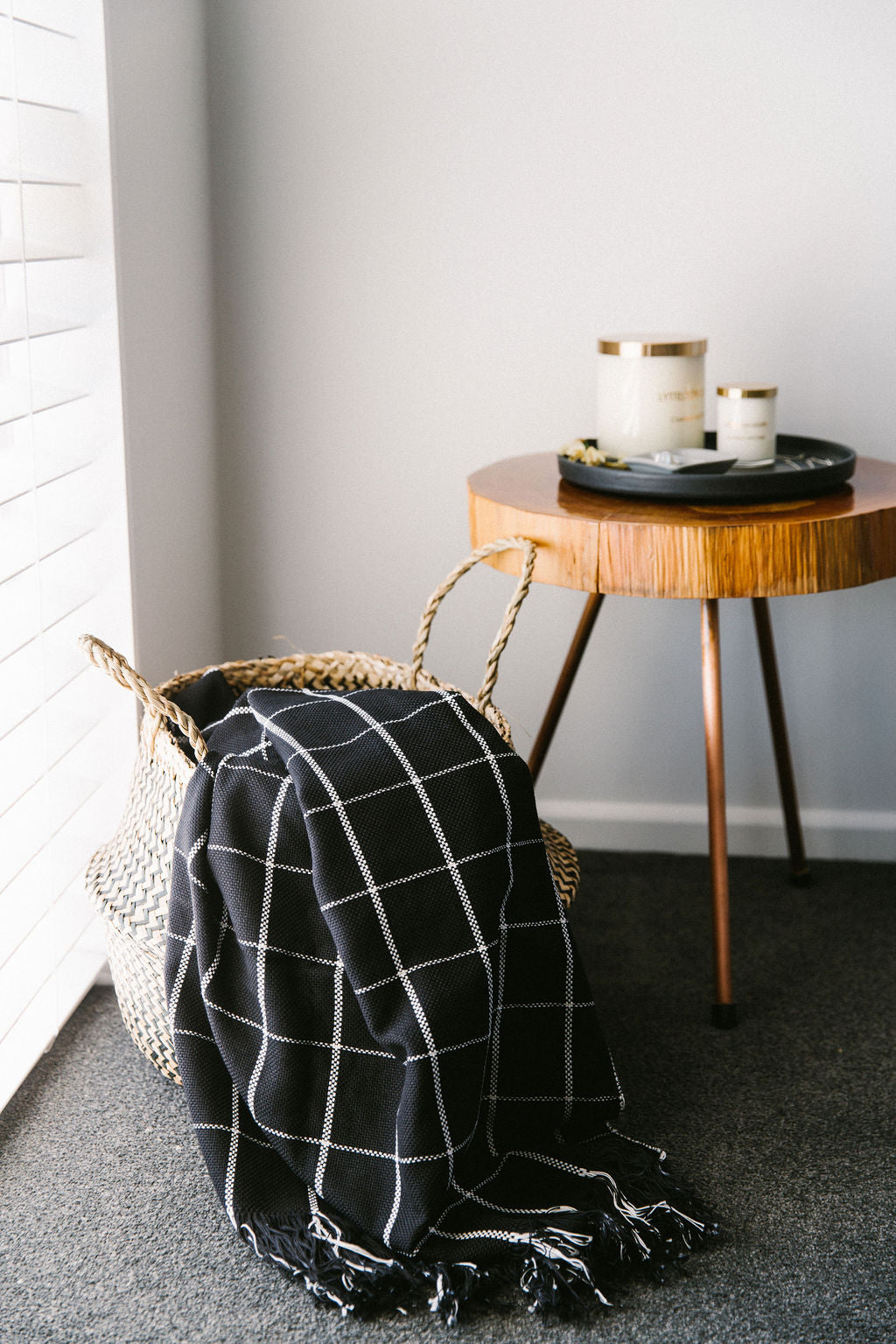Black checkered blanket draped over a chair next to a wooden side table with candles.