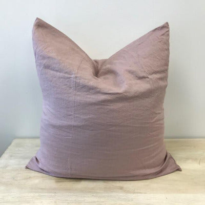 A blush coloured European size microfibre Pillow with a French flax linen cover, styled with a chopped centre on a light wood surface with a light background.