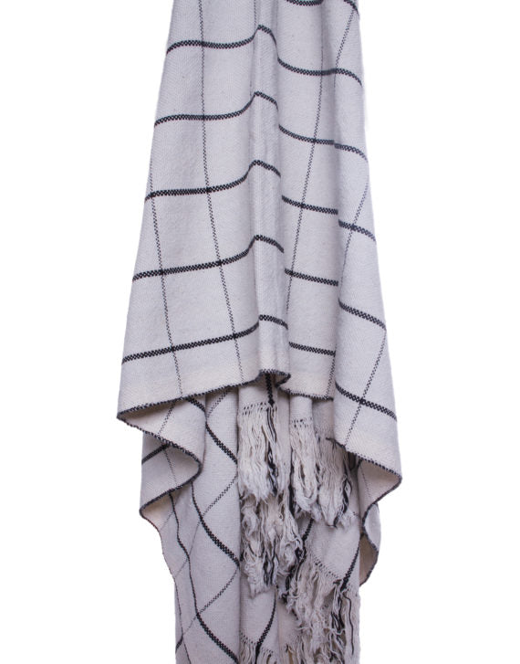 white and black check blanket draped across a flat white surface, close up view