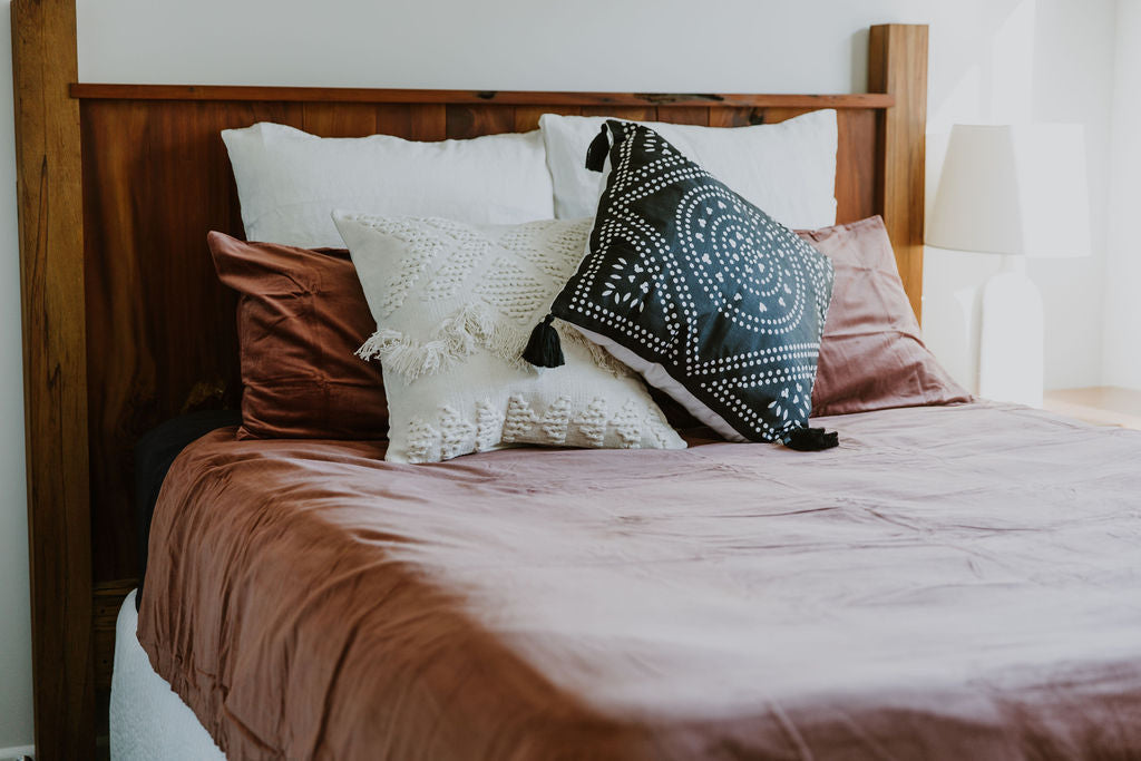 Bed with decorative kim soo throw pillows and a wooden headboard in a bedroom setting.