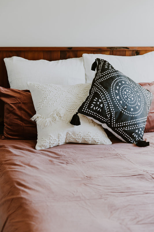Decorative Kim Soo black and white pillows on a bed with a wooden headboard and a dark pink duvet
