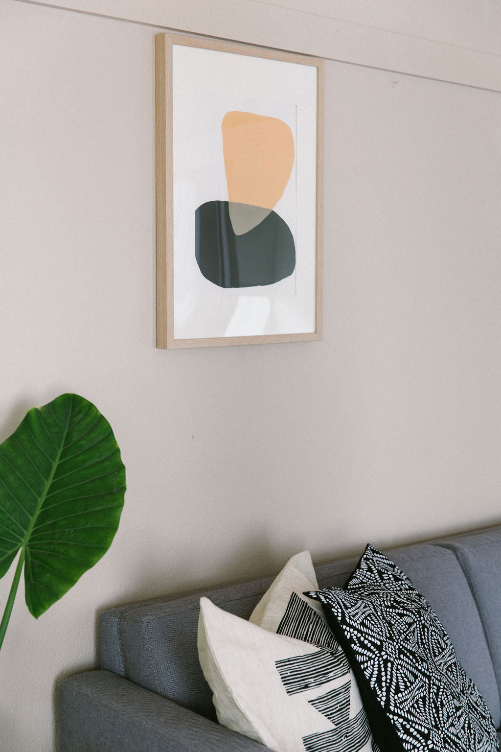 Framed abstract art on a wall above a grey sofa with decorative pillows.