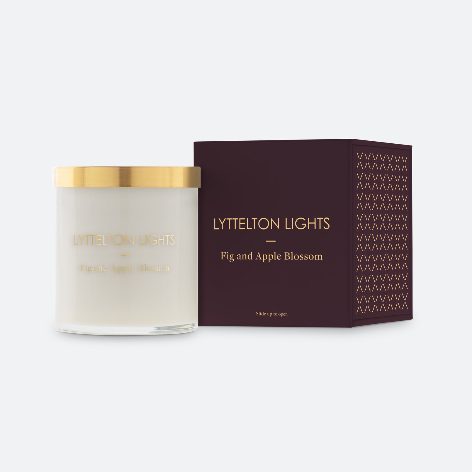 Lyttelton Lights Fig and Apple Blossom candle with gold lid and matching maroon packaging on a white background