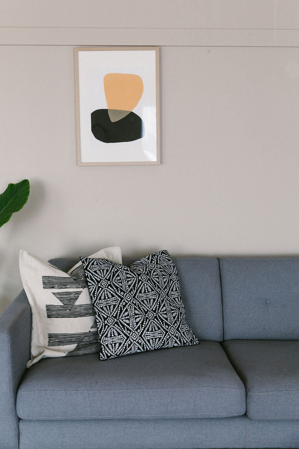 Gray sofa with patterned cushions and a framed sonora #4 abstract art piece on the wall.