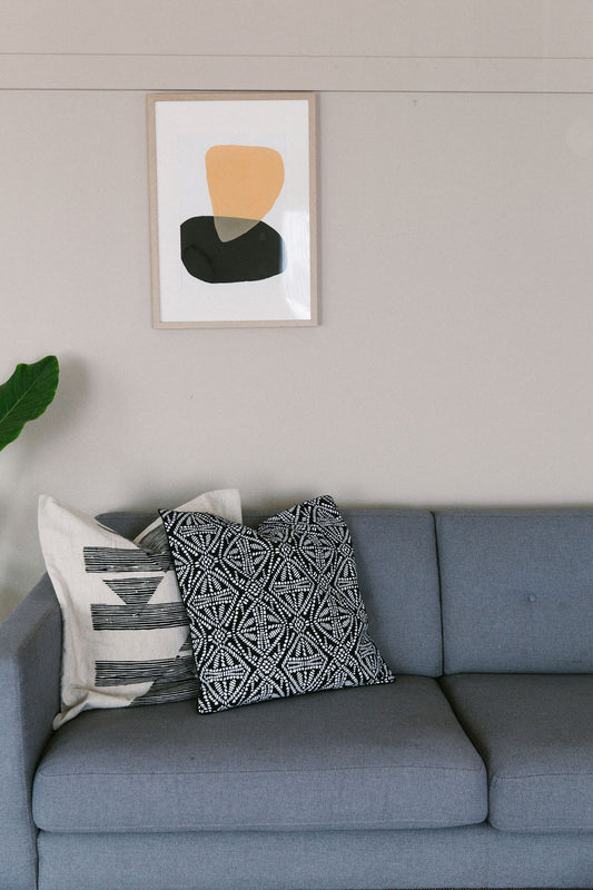 Gray sofa with patterned cushions and a framed sonora #4 abstract art piece on the wall.