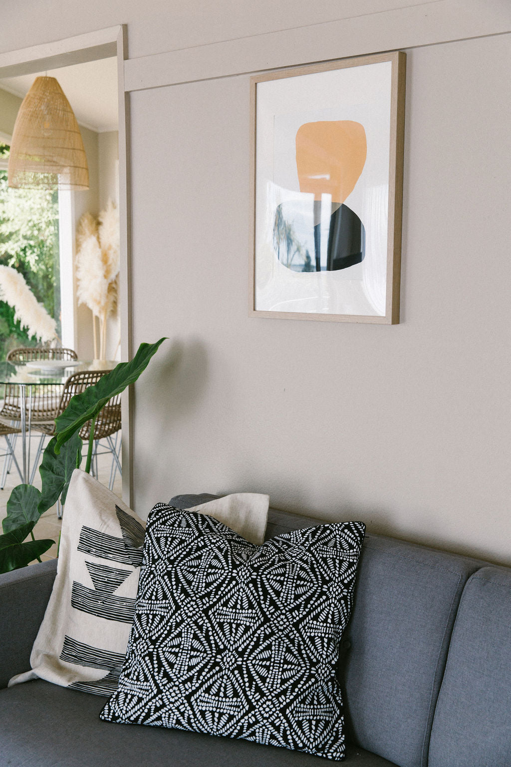 Decorative pillows on a grey sofa with a framed sonora series #4 abstract art piece on the wall.