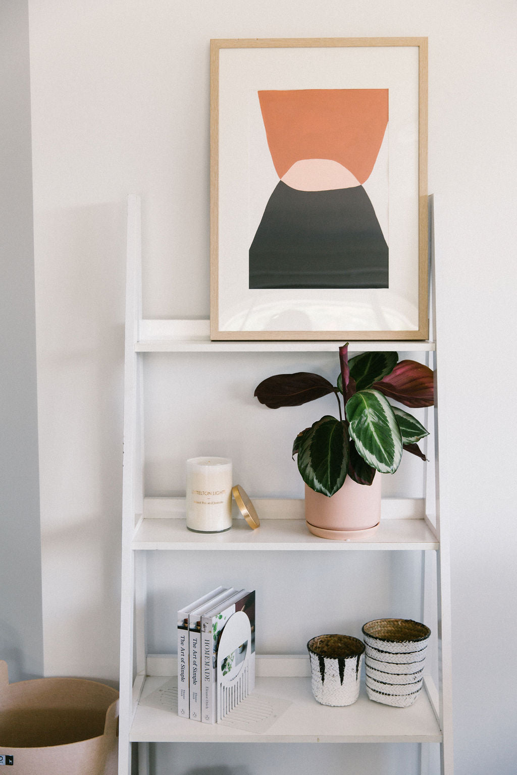 White bookshelf with decorative items including a plant, books, and a framed Sonora Series #6 artwork by Kim Soo.