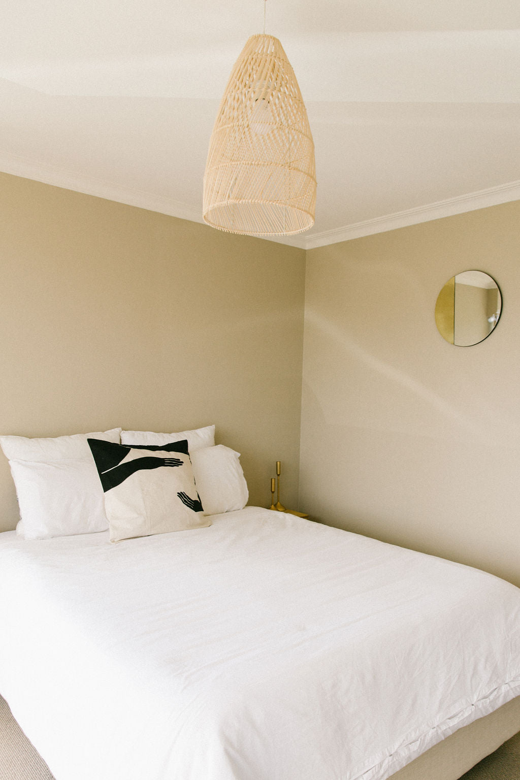Neatly made bed with white bedding and decorative kim soo resistance printed pillows in a bedroom setting.