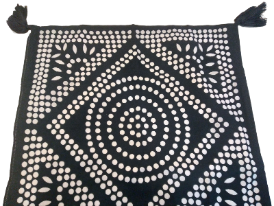 Close up detail of a kim soo dot print, hand screened cushion cover with tassels on a white background.