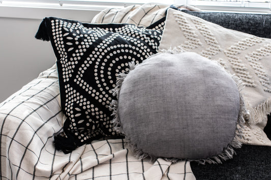 Decorative pillows on a sofa with a neutral color scheme on a white and black checkered throw blanket